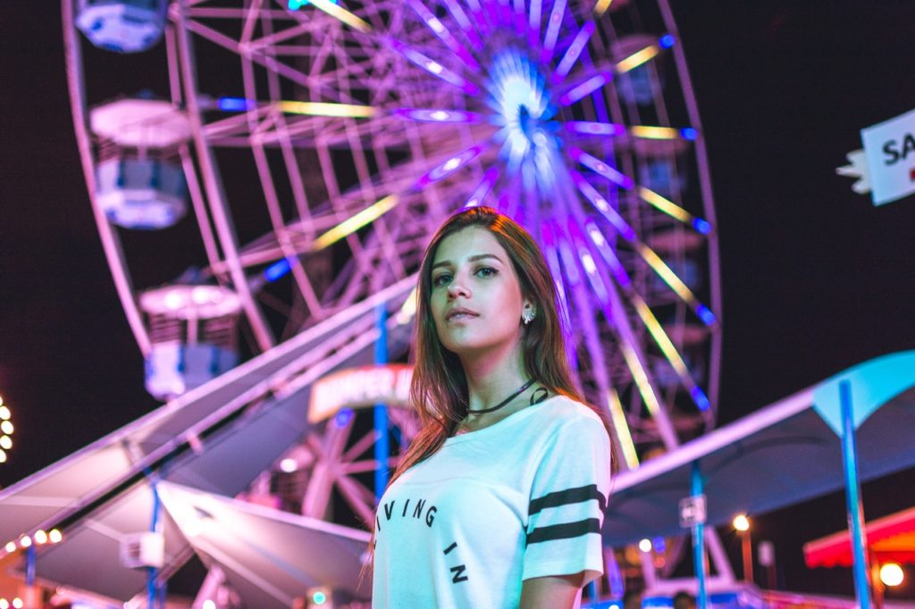 Woman standing in front of Ferris Wheel at music festival